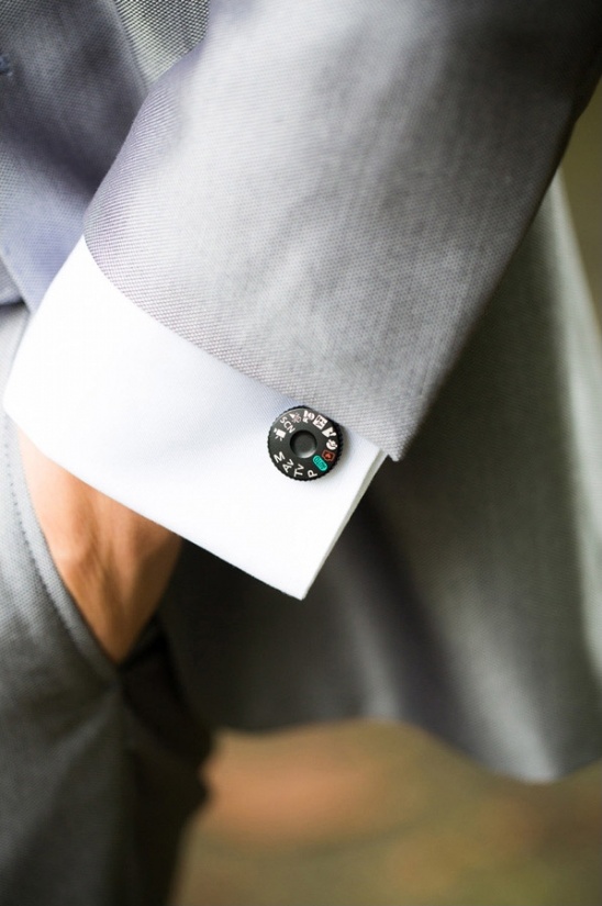Man in gray suit shows off a creative cufflink detail