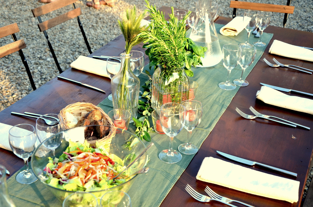 Elegant outdoor dining table setting with salad and flowers