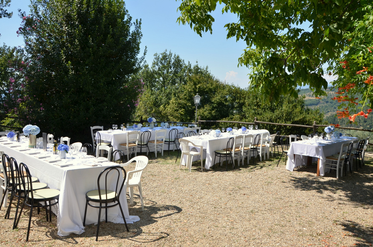 Outdoor wedding reception tables set with white linens and flowers