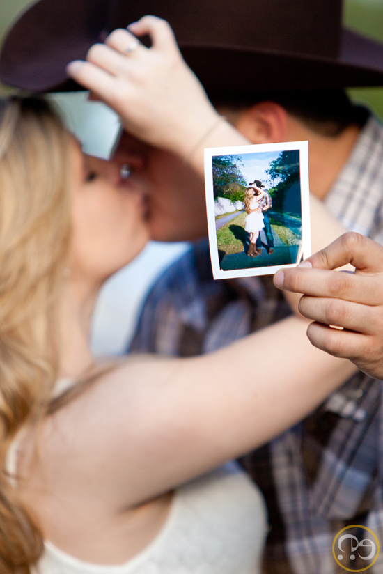 Couple kissing with a polaroid photo, cowboy hat in the background