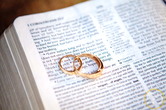 Two golden wedding rings on an open bible page with text