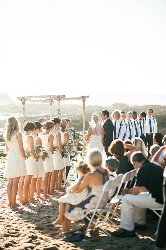 Beach wedding ceremony with bridesmaids and guests