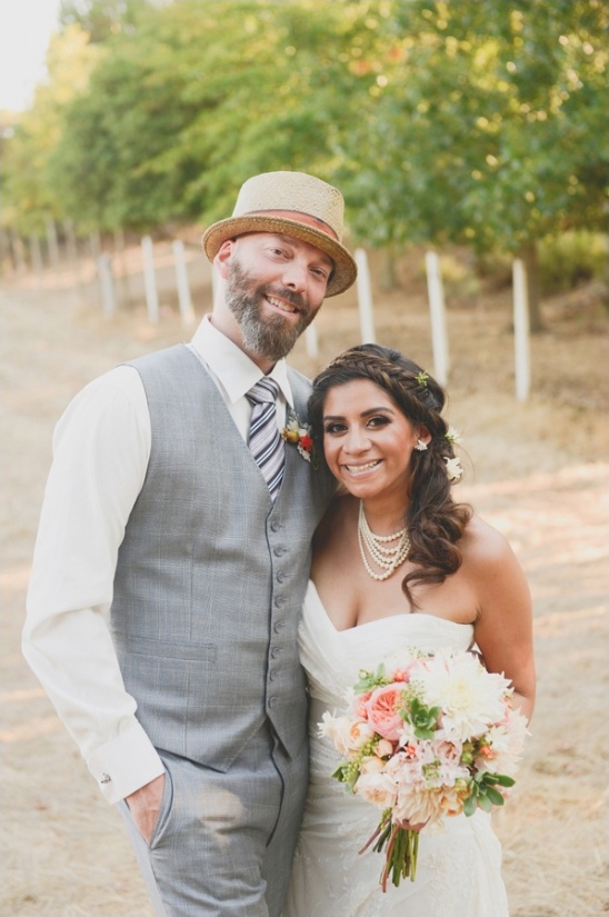 Happy couple on their wedding day, smiling outdoors with bouquet
