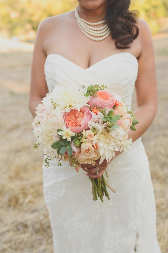 Bride in a lace dress holding a beautiful floral bouquet