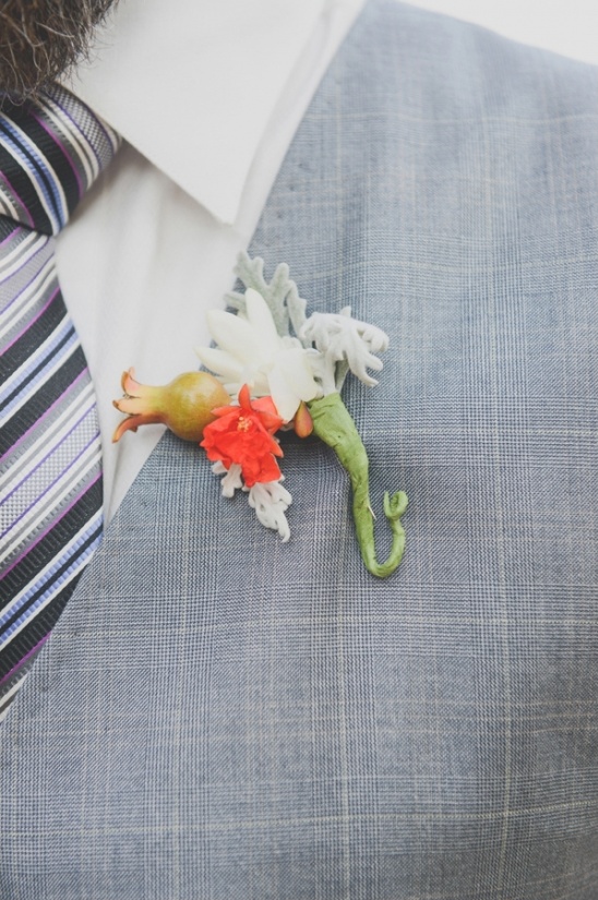 Groom's boutonniere with pomegranate and floral accents on suit