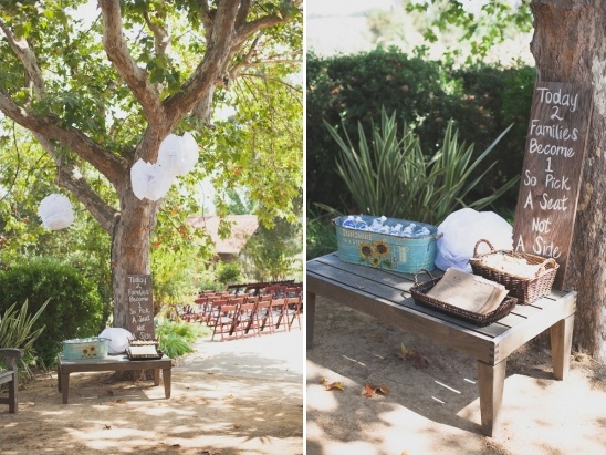 Outdoor wedding sign near a tree invites guests to seat together, not sides