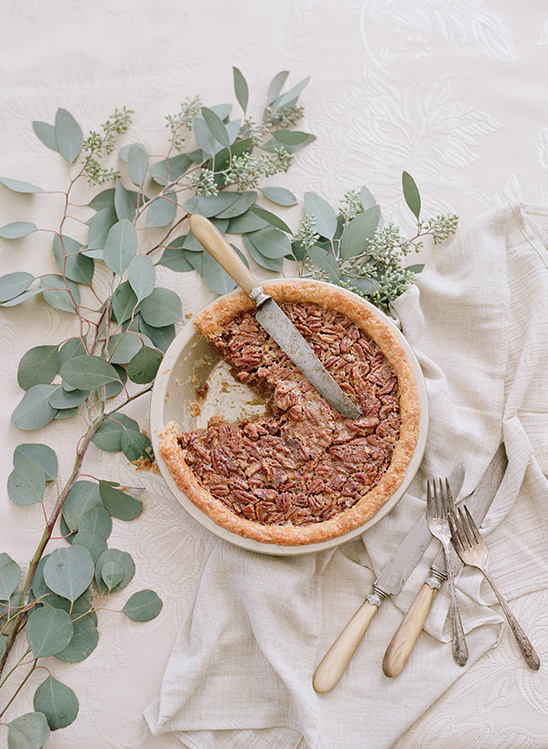 Delicious pecan pie on a table with eucalyptus leaves and cutlery