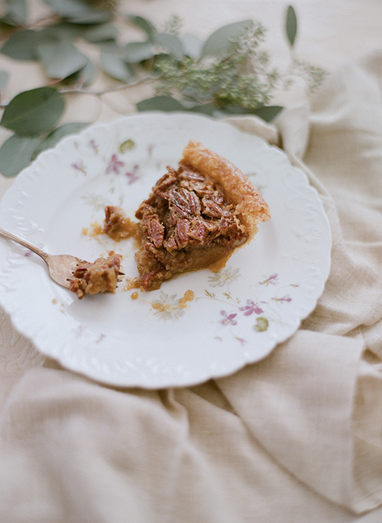 Slice of pecan pie on a floral plate with a fork, cozy aesthetic