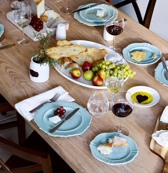A beautifully set table with appetizers, wine, and a feast laid out
