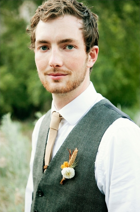 Handsome groom wearing a herringbone vest and boutonniere