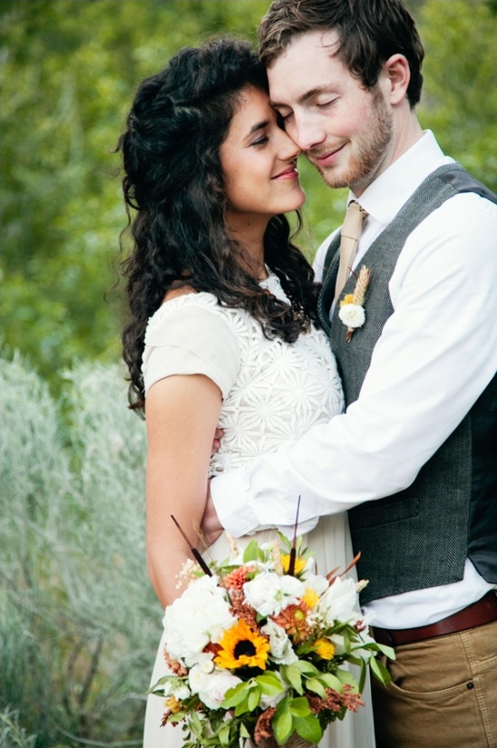 Happy bride and groom embracing, holding bouquet