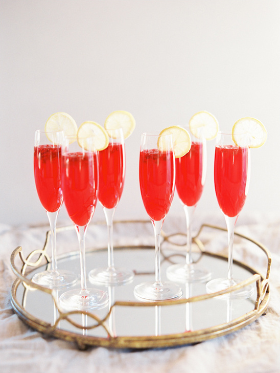 Red cocktails with lemon slices on a gold tray
