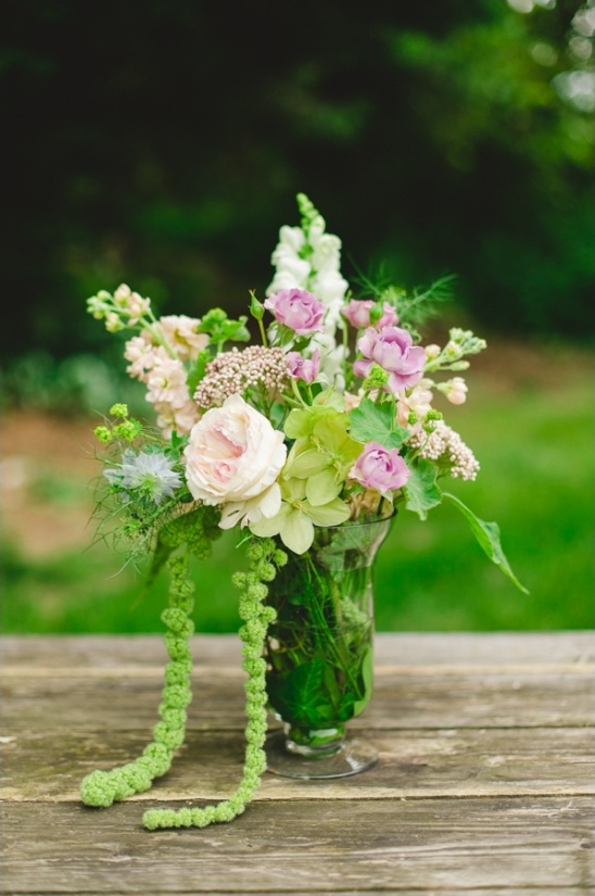 Floral bouquet in a clear vase on wooden table outdoors