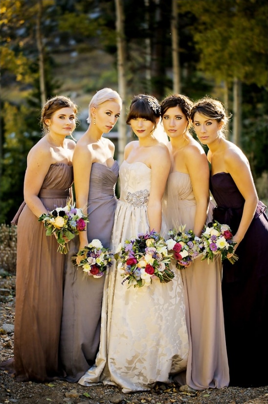 Bride and bridesmaids in autumnal gowns, holding bouquets
