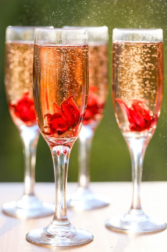 Sparkling cocktail glasses with red flower petals