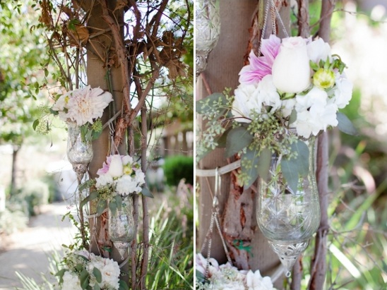 Hanging floral decor in glass vases on tree branches