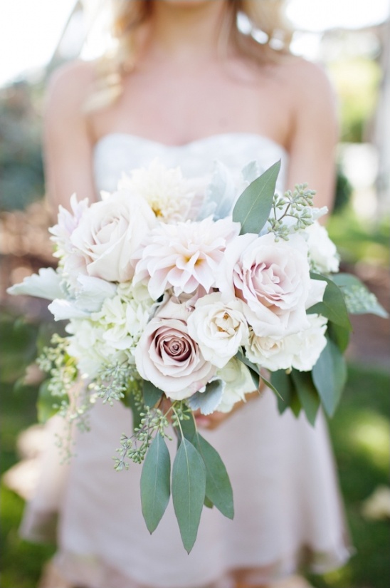 Bride holds a bouquet of white and blush wedding flowers