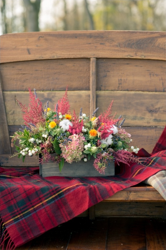 Rustic wooden bench with flowers and tartan blanket