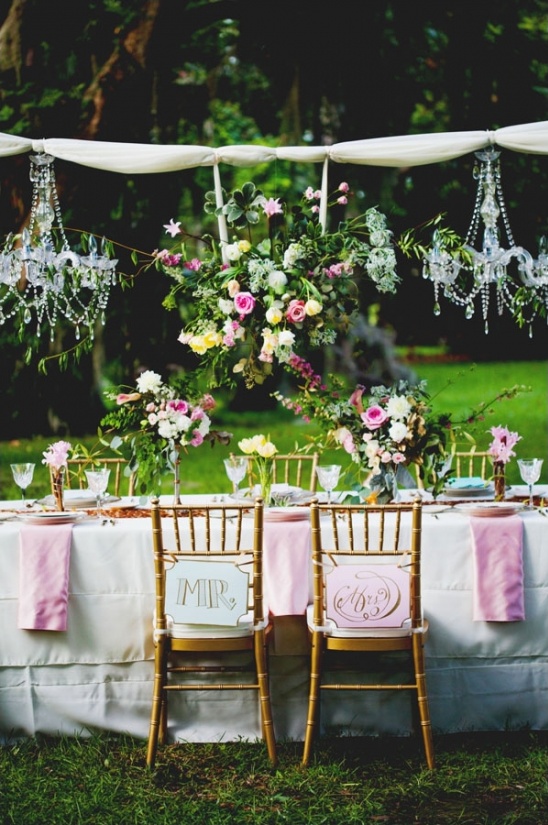 Outdoor wedding table with floral decor and chandeliers
