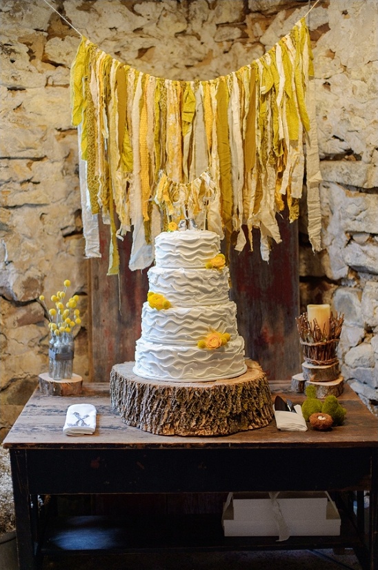 Rustic wedding cake with yellow flowers on wood stand