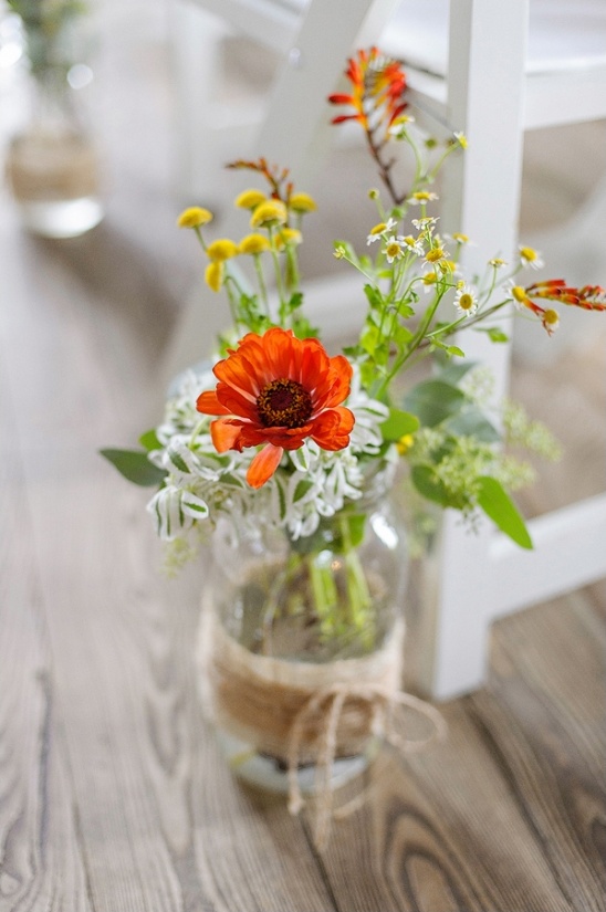Rustic floral arrangement in a mason jar on wood floor