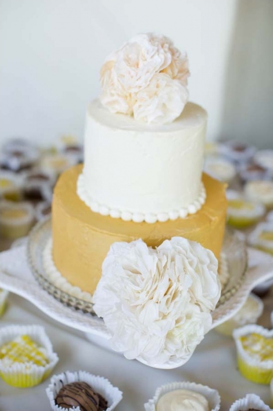 Two tier cake with flower decorations and cupcakes