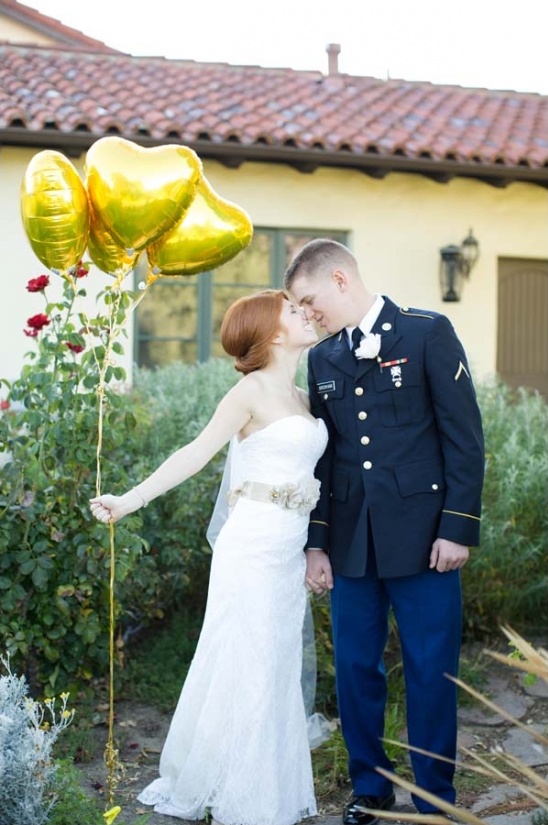 Bride and groom in military uniform kiss with balloons