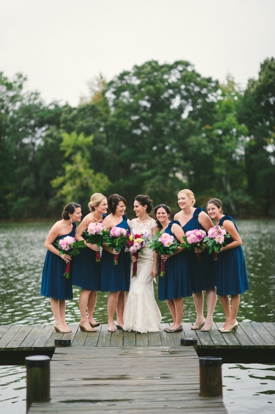 Bride and bridesmaids in blue dresses pose on a dock