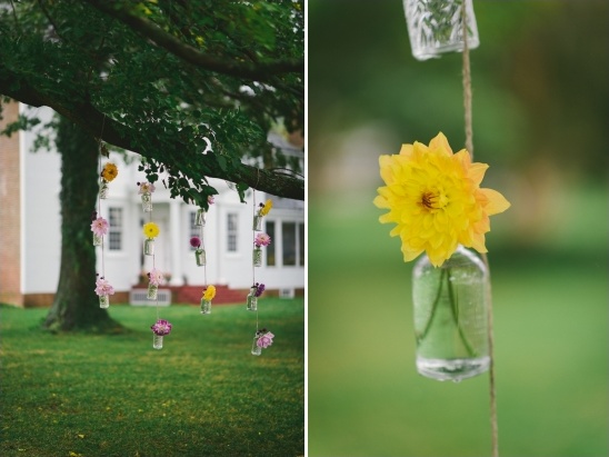 Flower arrangements in glass jars hanging from tree