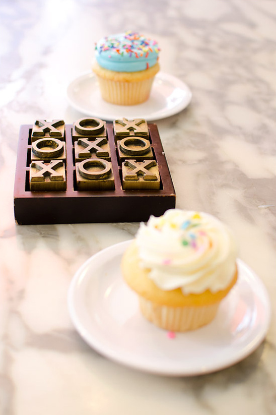 Tic-tac-toe game and cupcakes on marble table