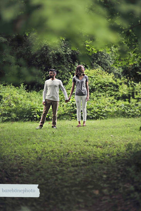 Couple holding hands, walking in a lush green forest