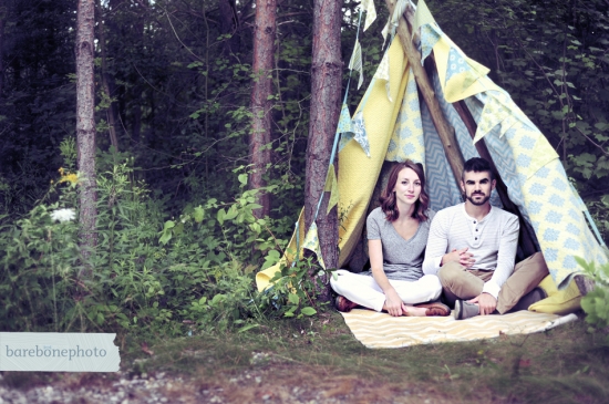 Couple sitting inside whimsical teepee in woods
