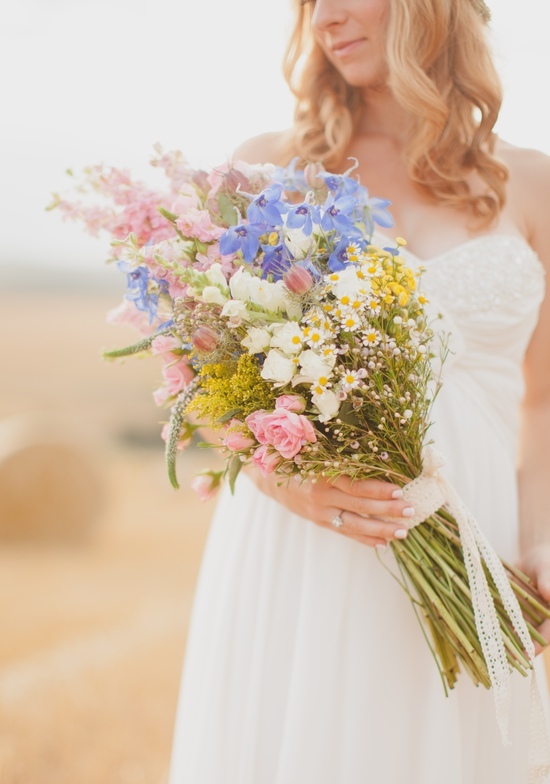 Bride holds colorful wildflower bouquet in white dress