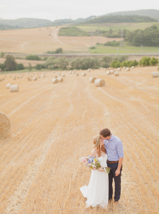 Bride and groom kiss in field of hay bales wedding