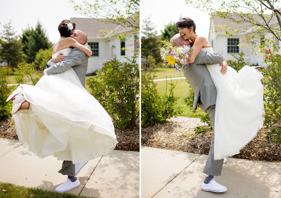 Groom lifts laughing bride on wedding day outside