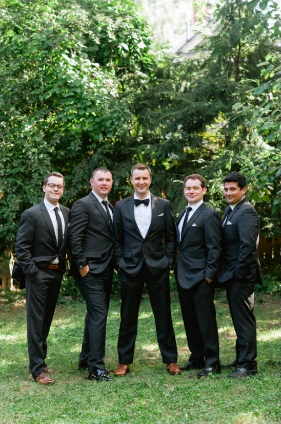 Groomsmen in black suits posing outdoors