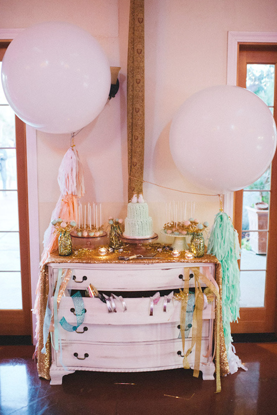 Pastel birthday party dessert table with balloons and streamers