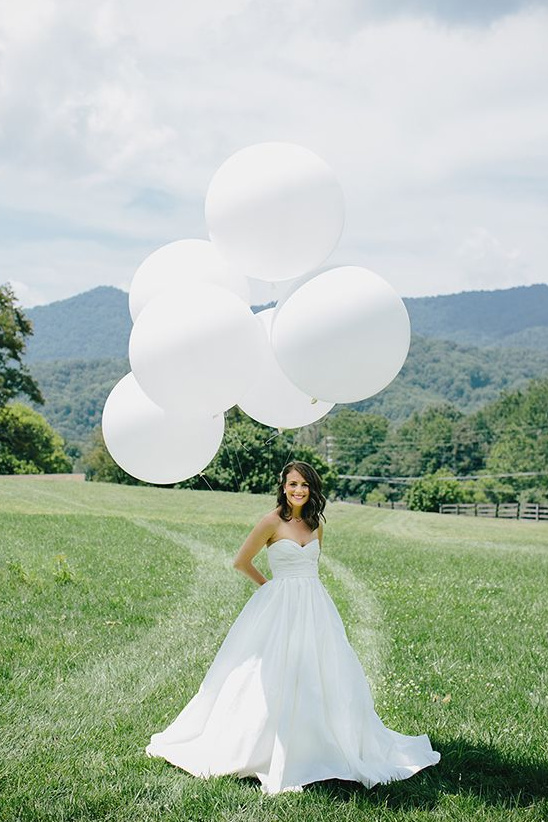 Bride holding white balloons outdoor wedding portrait