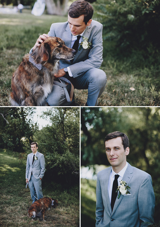 Groom in gray suit pets dog with bowtie outdoors