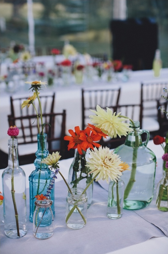 Colorful wildflowers in vintage bottles decorate table