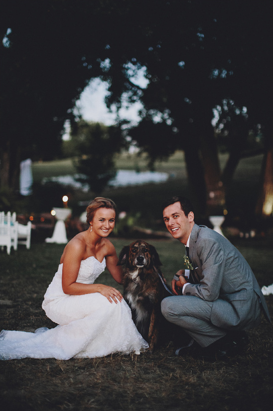 Happy couple poses with their dog at their wedding