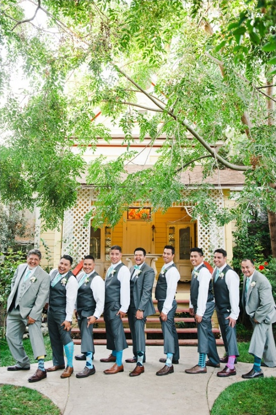 Groomsmen in gray suits and teal socks pose outside