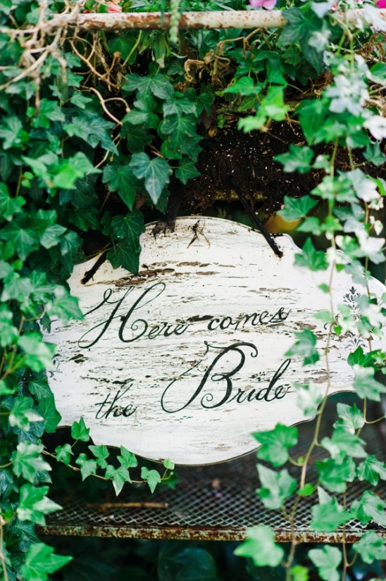 Rustic Here comes the Bride sign framed by green ivy