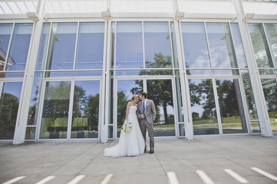 Bride and groom kiss at modern glass building venue