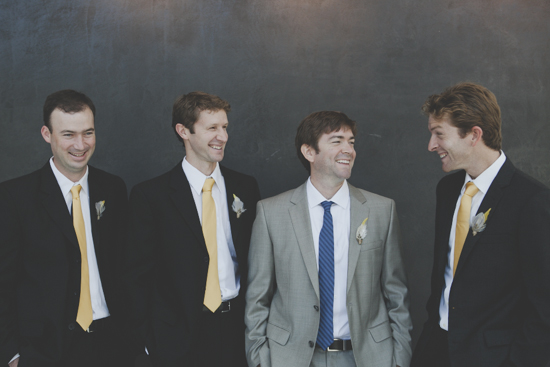 Groomsmen in suits laugh at a wedding reception