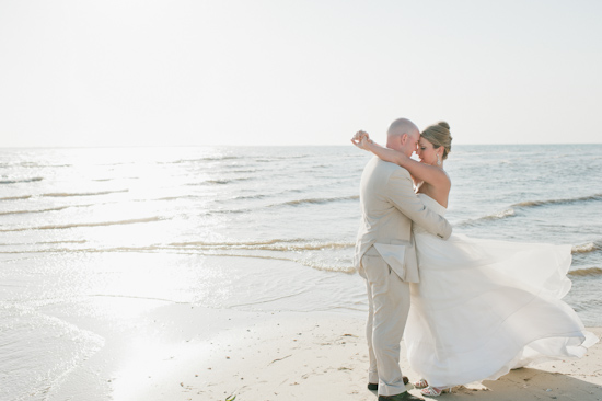 Bride and groom embrace on a sunny beach wedding day