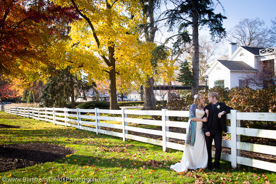 Autumn wedding couple by white fence