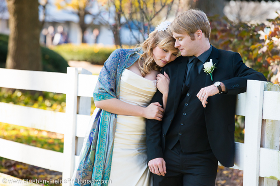 Happy bride and groom embracing by white fence
