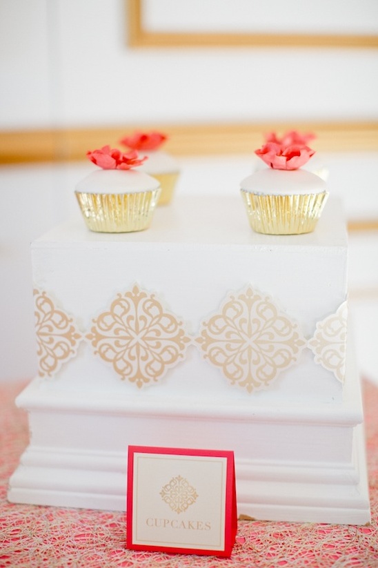 Elegant coral-topped cupcakes on a white stand
