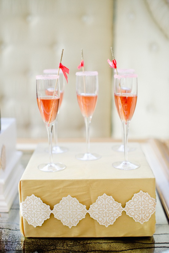 Pink champagne flutes with ribbon garnish on gold display